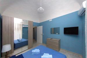 een blauwe slaapkamer met een bed en een televisie bij Patrì House in Catania