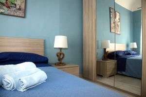 een blauwe slaapkamer met een bed en een spiegel bij Patrì House in Catania