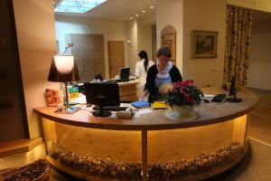 a woman standing at a desk in an office at Alp Wellness Sport Hotel Panorama in Fai della Paganella +137 photos