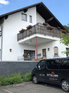 un furgone nero parcheggiato di fronte a una casa bianca. di Gästehaus Rehwinkel ad Allenbach