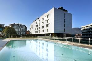 a large swimming pool in front of a building at Occidental Bilbao in Bilbao