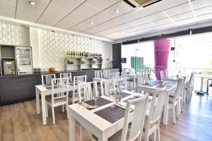 a dining room with white tables and white chairs at Bayside Salgados in Albufeira