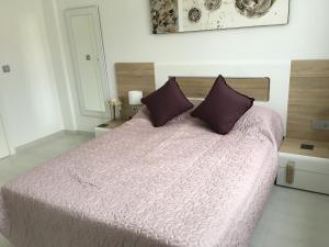 ein Schlafzimmer mit einem großen Bett mit lila Bettwäsche und Kissen in der Unterkunft Boulevard La Zenia Villa in Playa Flamenca
