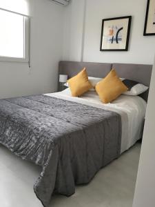 a bedroom with a large bed with yellow pillows at Boulevard La Zenia Villa in Playa Flamenca