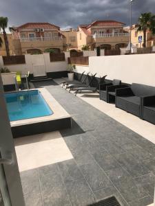 um pátio com cadeiras e uma piscina num edifício em Boulevard La Zenia Villa em Playa Flamenca