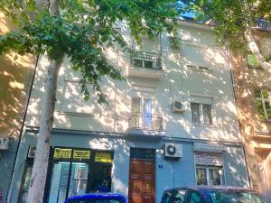 un edificio blanco con coches estacionados frente a él en Apartments Selfie Belgrade Central, en Belgrado