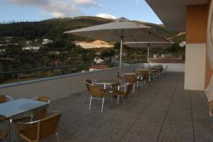 uma fila de mesas e cadeiras com guarda-sóis numa varanda em Hotel Sao Pedro em Arouca