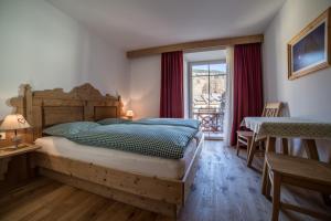 ein Schlafzimmer mit einem großen Bett und einem Fenster in der Unterkunft Appartementhaus Sapelza in Toblach