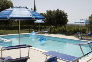 a swimming pool with two chairs and an umbrella at Casa Vacanze Valdamone in Suvereto