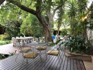eine Holzterrasse mit Stühlen, einem Tisch und einem Baum in der Unterkunft The Wild Fig in Durbanville
