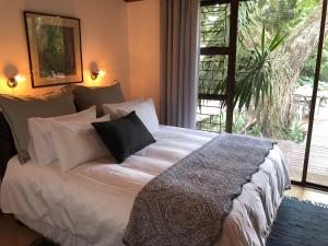 a bedroom with a white bed with pillows and a window at The Wild Fig in Durbanville
