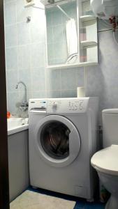 a washing machine in a bathroom next to a toilet at Apartments in the Center of the city in Dnipro