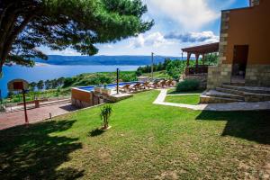 a yard with a view of the water and a house at Villa Jozini trudi in Lokva Rogoznica
