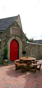 een picknicktafel voor een gebouw met een rode deur bij James John Hamilton House and backpacker hostel in Fishguard