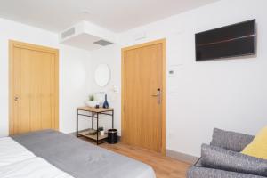 a bedroom with a bed and a couch and a flat screen tv at Pensión Arroka in San Sebastián