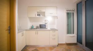 una pequeña cocina con armarios blancos y microondas en Apartments S&A en Zagreb
