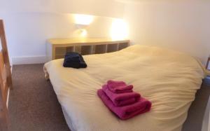 a white bed with two pink towels on it at Harrington Gardens in London