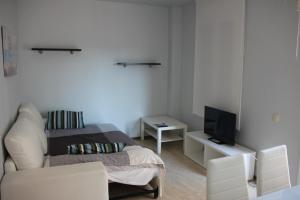 a white room with a bed and a tv at Apartamentos Caru in Castelldefels