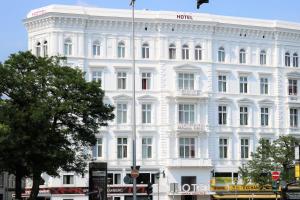 ein weißes Gebäude in einer Stadtstraße mit einem Baum in der Unterkunft Novum Hotel Graf Moltke Hamburg in Hamburg