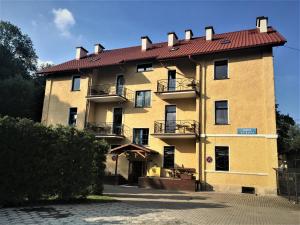 a large yellow building with a red roof at Hotel Europa in Polanica-Zdrój