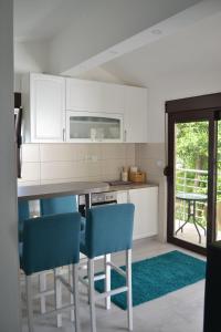 a kitchen with white cabinets and blue chairs at Apartments Niković in Risan