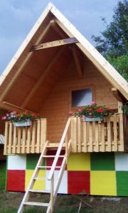 uma casa de brincar com um telhado de cor arco-íris e escadas em farmglamping Planika - Encijan em Hraše