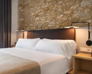 a bedroom with a large white bed and a stone wall at Alta House Begur in Begur