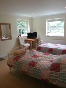 a bedroom with two beds and a desk and two windows at Rosmerryn in Constantine