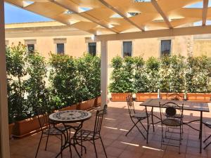 een patio met tafels, stoelen en planten bij B&B L'Assunta in Alessano