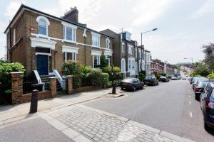 a street with houses and cars parked on the street at Veeve - Timeless Family Home in London