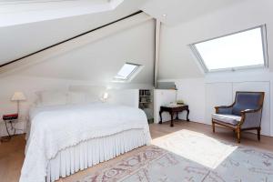 a bedroom with a bed and a chair and a window at Veeve - Timeless Family Home in London