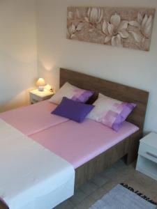 a bedroom with a bed with pink sheets and purple pillows at Kuća za odmor Matko House Matko in Pag