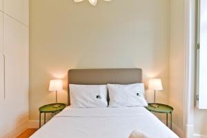 een slaapkamer met een wit bed en 2 bijzettafels bij BmyGuest - Arroios Cosy Apartment in Lissabon