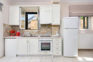 uma cozinha com armários brancos e um frigorífico em Tesori Dassia Villas By Hotelius em Dassia