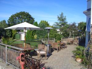 patio ze stołami, krzesłami i parasolem w obiekcie Malin House Hotel w mieście Saundersfoot