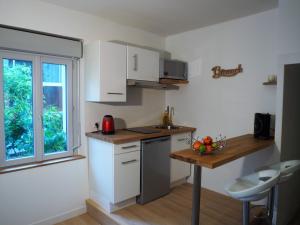 una cucina con mobili bianchi, un tavolo e una finestra di Studio moderne, hypercentre de Cholet, arrivée autonome ! a Cholet