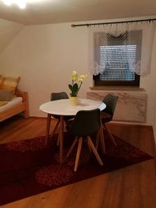 a dining room table with chairs and a vase of flowers at Ferienwohnung Edda in Ebensfeld
