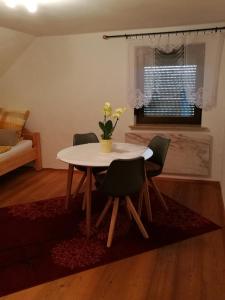 une table à manger avec des chaises et un vase de fleurs dans l'établissement Ferienwohnung Edda, à Ebensfeld