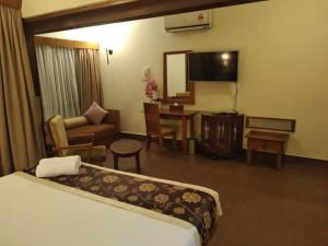 a hotel room with a bed and a desk and a television at Langkawi Lagoon Resort Water Chalet in Pantai Cenang