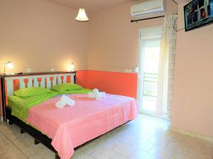 a bedroom with a bed with green sheets and a window at Zako Apartments in Limenaria