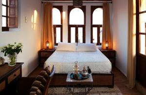a bedroom with a bed with windows and a table at Dar Mo'Da in Marrakesh