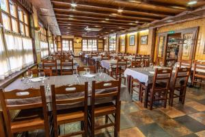un comedor con mesas, sillas y ventanas en Hotel Peña Pandos en Felechosa