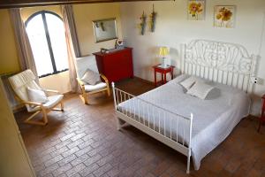 a bedroom with a bed and two chairs and a window at Podere Chiocciola in Poggibonsi