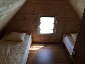 two beds in a wooden room with a window at Domki na Morskiej in Łukęcin