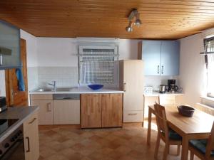 アーレンにあるフェリエンヴォーヌング ヴァーグナーの白いキャビネットと木製の天井が備わるキッチン