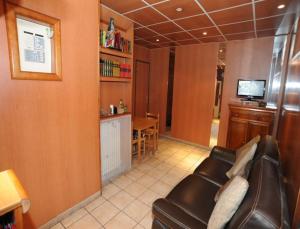 - un salon avec un canapé en cuir et une télévision dans l'établissement Sully Hôtel, à Paris