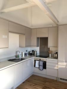 a white kitchen with white cabinets and a sink at No 3 Old Printworks in Winchester