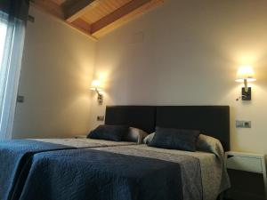 a bedroom with two beds with blue sheets and lights at Apartamentos La Encina in Celorio