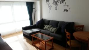 a living room with a black couch and a table at La Casa de Alba in Gijón