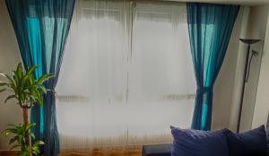 a large window with blue curtains in a living room at La Casa de Alba in Gijón